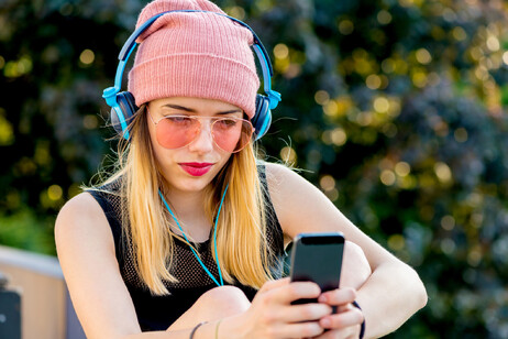 Una ragazza con cuffie e smartphone foto iStock.